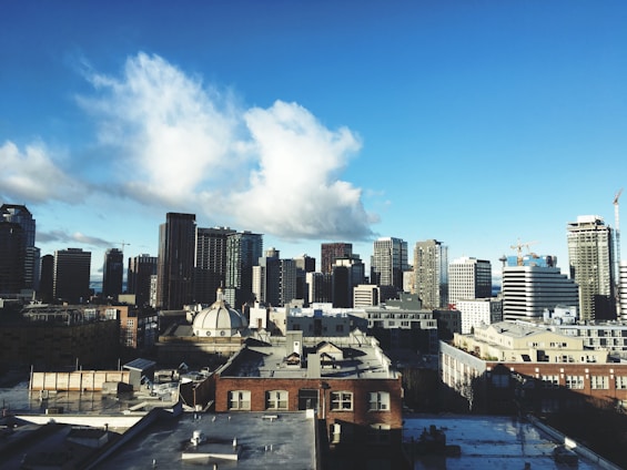 A dynamic city skyline with cranes and construction activity under a clear blue sky.