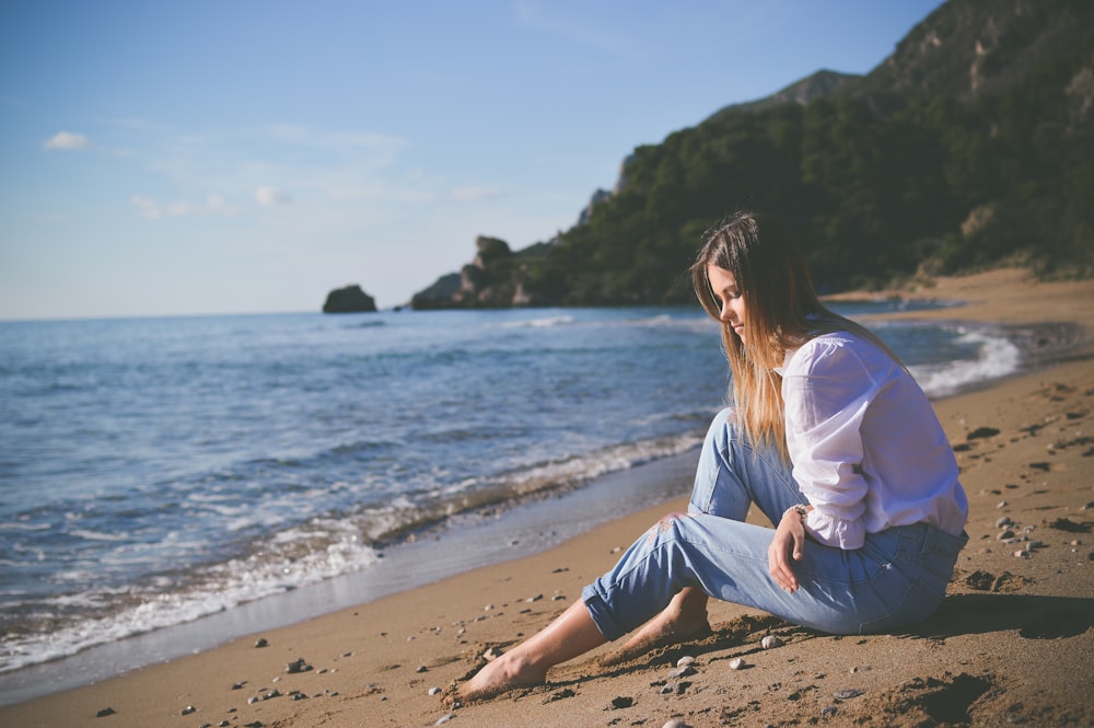 낮에 해변 해변에 앉아있는 여자
