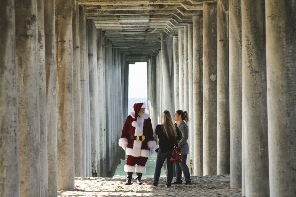 Santa Claus talking to woman near concrete post