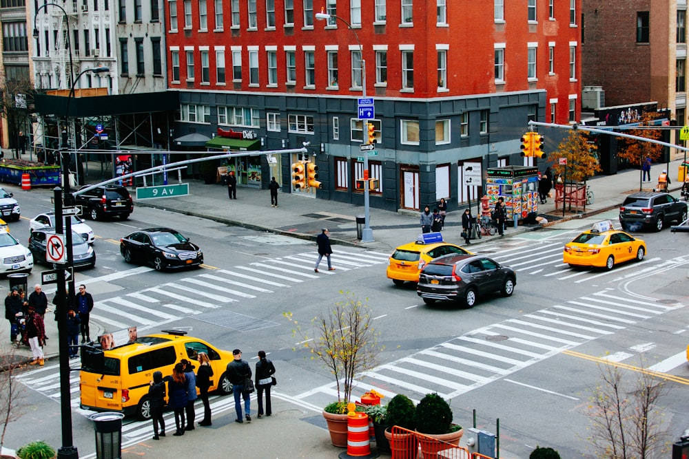 people walking on pedestrian lane near cars and buildings during daytime