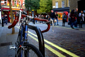 A close-up of hands locking an e-bike on a modern bike rack on a busy urban street.
