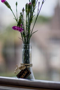 Elegant glass bottle of glowing body oil with fresh flowers nearby.