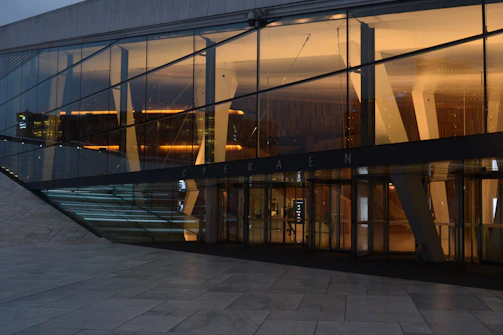 Nighttime exterior shot of a minimalist concrete and glass house with warm interior lighting.