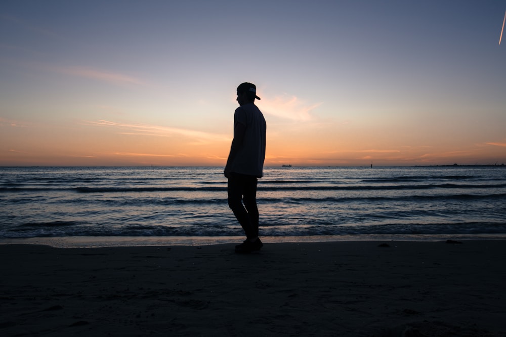 uomo in piedi sulla spiaggia durante il giorno