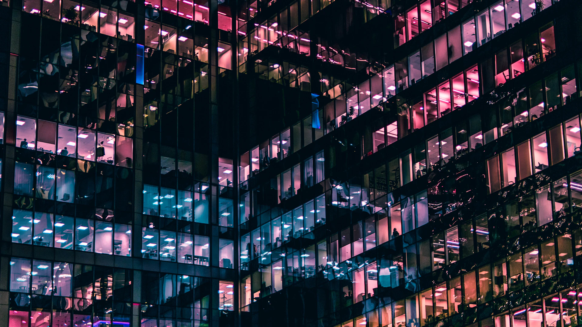 A modern building lit at night with people working inside