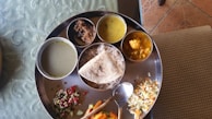 Traditional Indian thali served with various curries, rice, and breads on a brass plate.