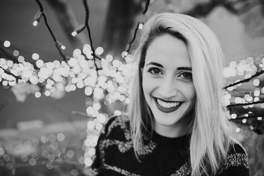 Photo en niveaux de gris d’une femme avec des guirlandes lumineuses