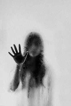 A chilling silhouette of a monster lurking behind a foggy window.