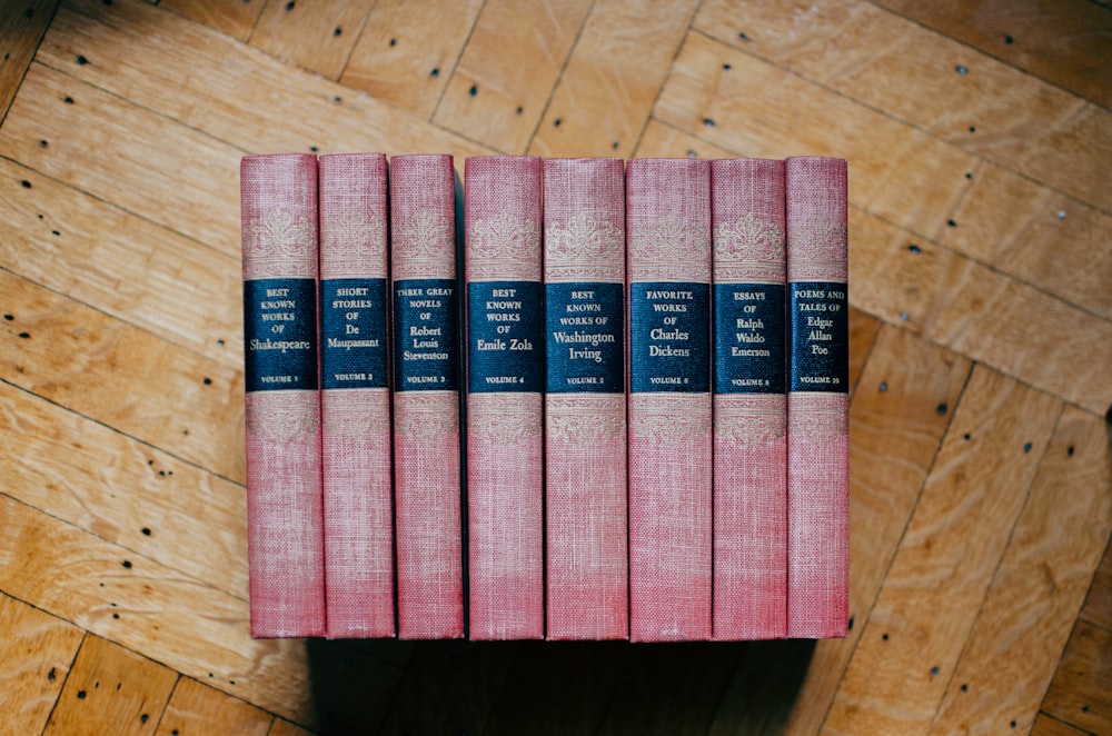 pile of red hardbound books on brown panel