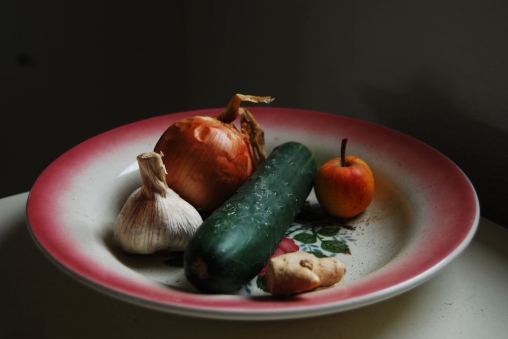 cebolla, ajo, jengibre y verduras verdes en un plato redondo blanco y rojo