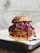A close-up of a golden, crispy Korean fried chicken sandwich with fresh slaw peeking out, set against a rustic wooden table.