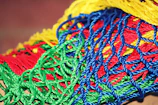 Variety of colorful plastic netting materials displayed on warehouse shelves.