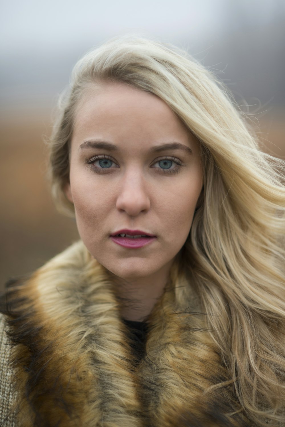 woman looking at camera wearing brown fur scarf