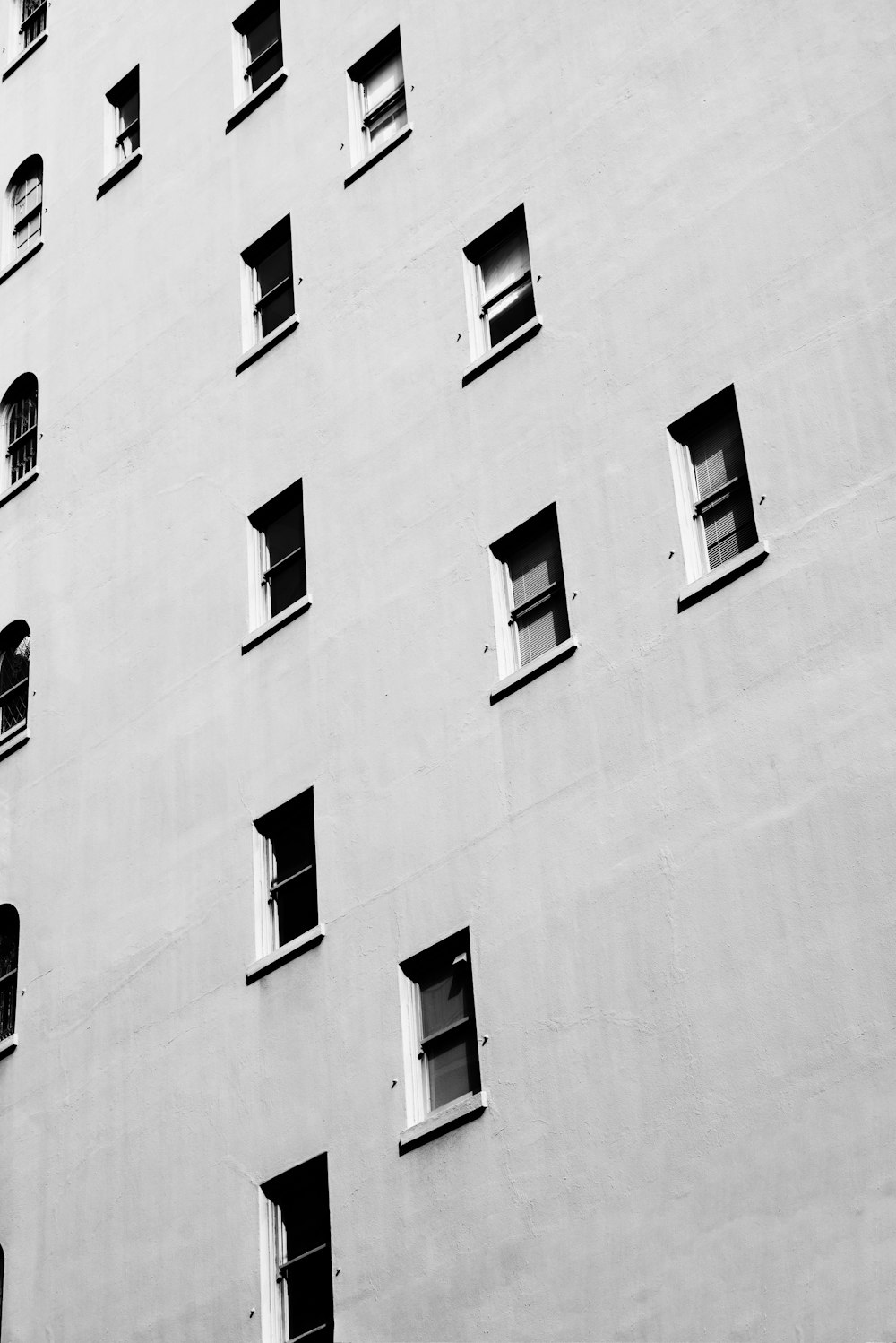 The exterior of a white building with randomly placed windows on each floor.