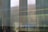 A blurred view through a reflective glass window showing faint outlines of structures outside, with a wheelchair accessibility symbol visible on the glass.