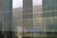 A blurred view through a reflective glass window showing faint outlines of structures outside, with a wheelchair accessibility symbol visible on the glass.