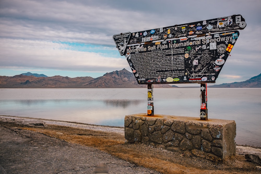 black and white board on gray concrete wall near body of water during daytime