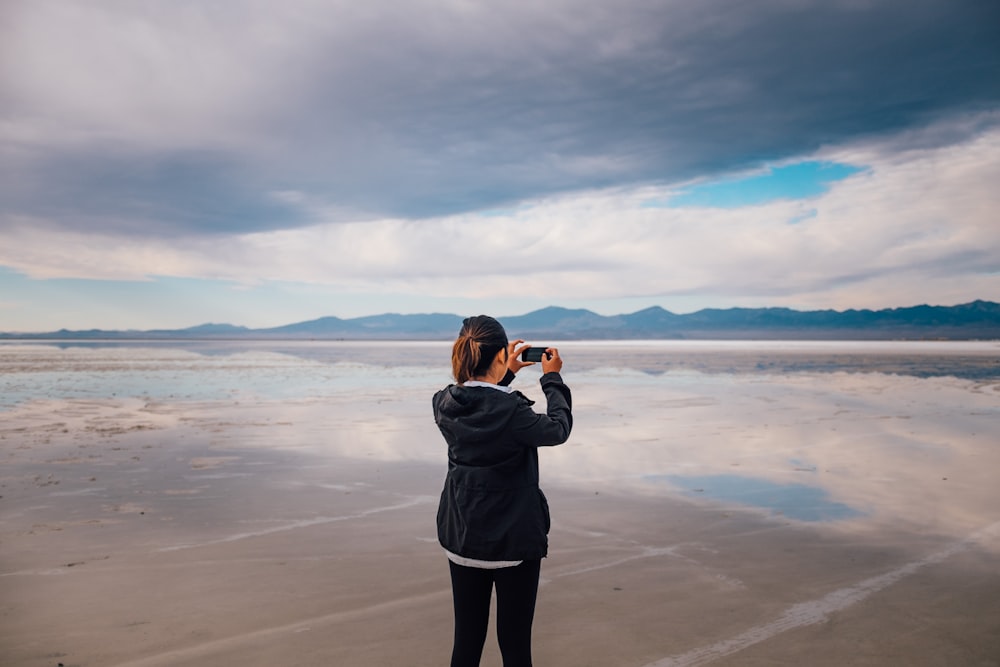 woman in gray jacket standing on beach during daytime