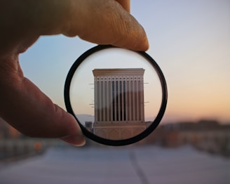 A sleek camera lens focused on a stylish modern building at dusk with soft shadows.