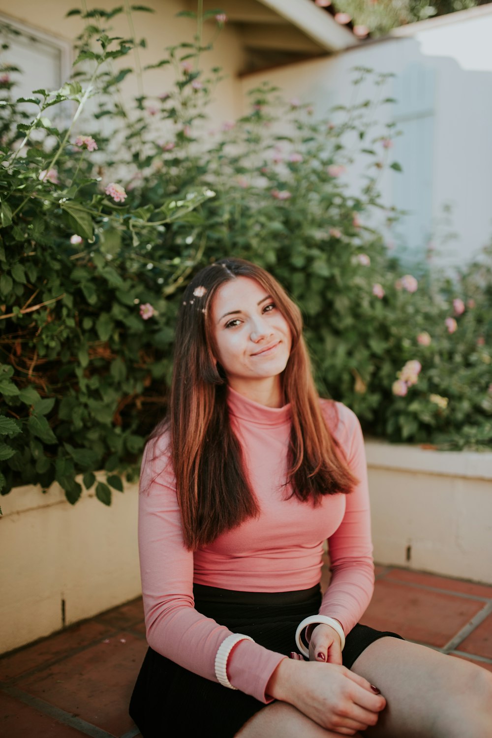 Mujer sentada cerca de flores rosadas durante el día