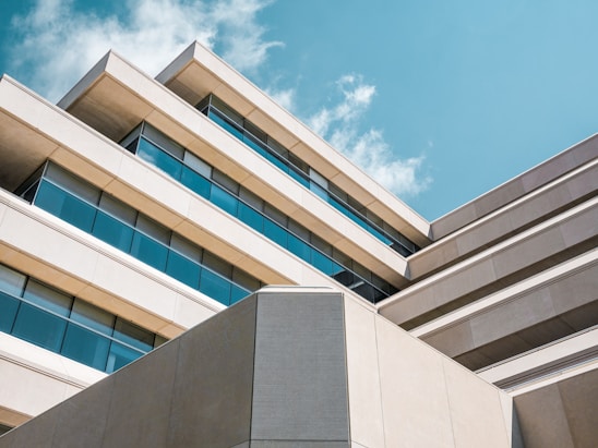 low angle photo of beige concrete building under cloudy sky