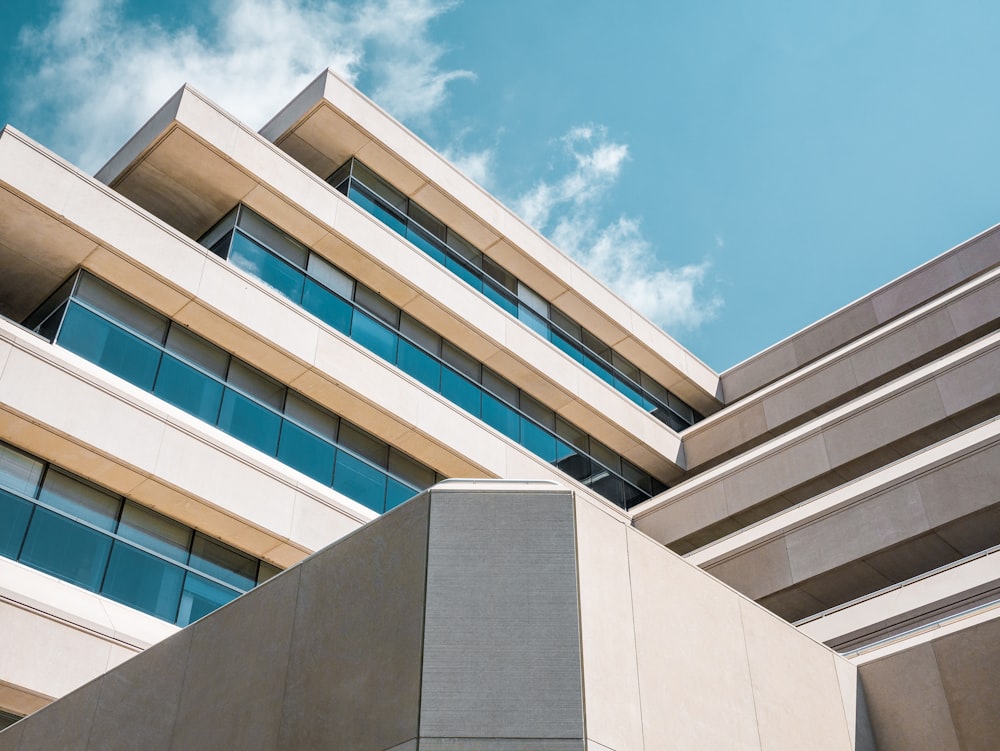 Photo en contre-plongée d’un bâtiment en béton beige sous un ciel nuageux