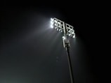 The gleaming pitch of Stamford Bridge under bright stadium lights at dusk.