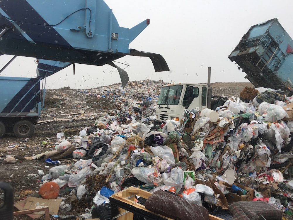 Bags of garbage getting emptied from trucks at a dump.