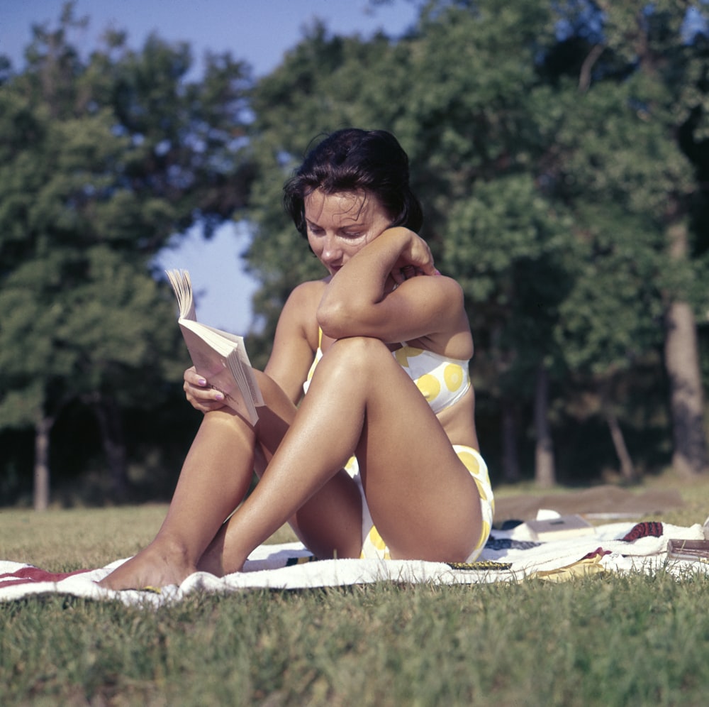 Frau sitzt auf Matte und liest Buch