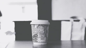 Close-up of a café menu and takeaway coffee cup featuring bright, fun illustrations and bold typography.