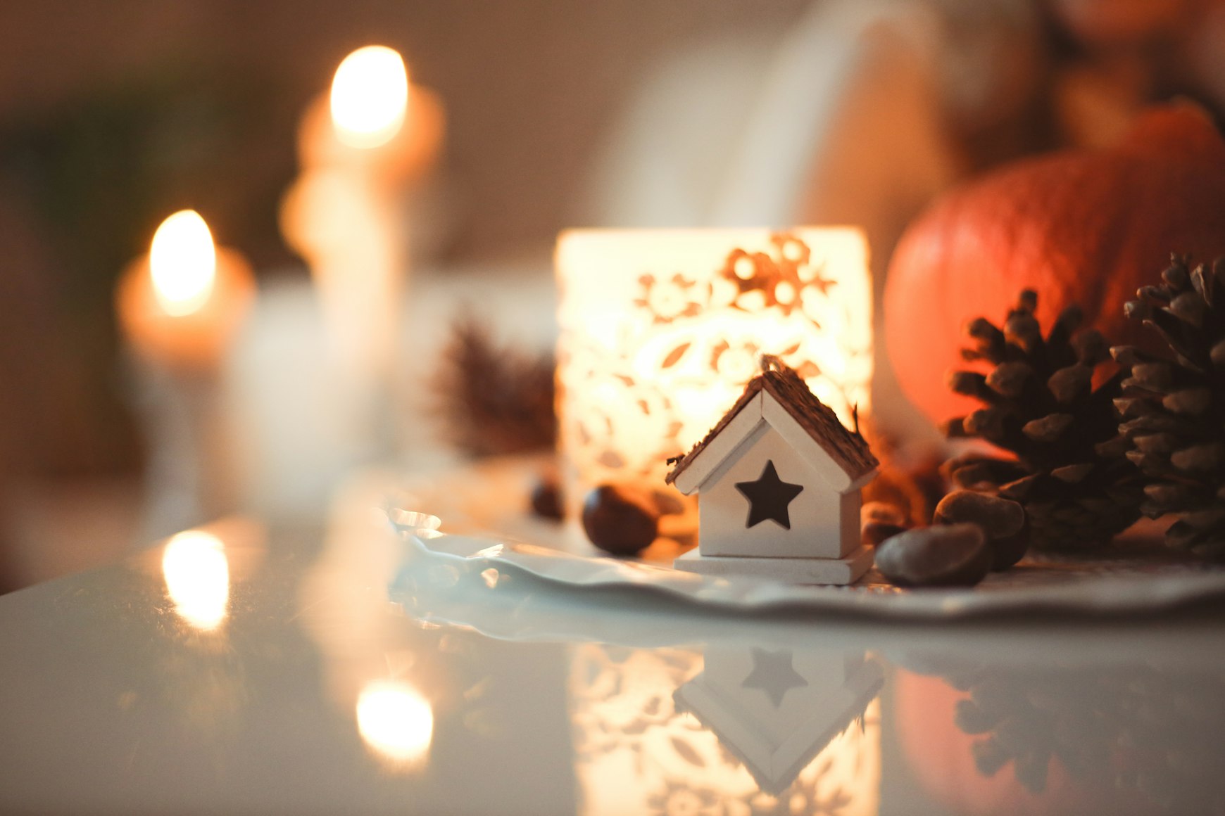 Holiday decoration of a small house next to a candle.
