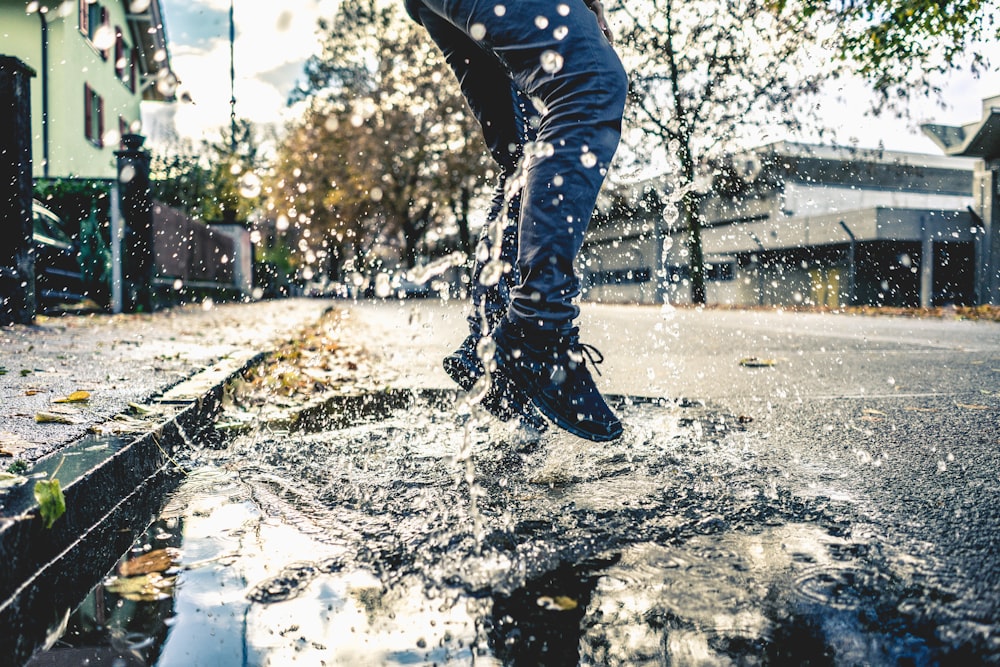 person making splash on water puddle on road