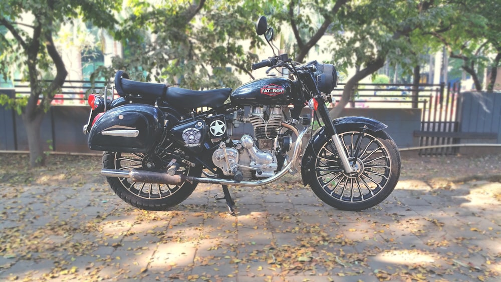 Motocicleta preta na calçada perto da árvore