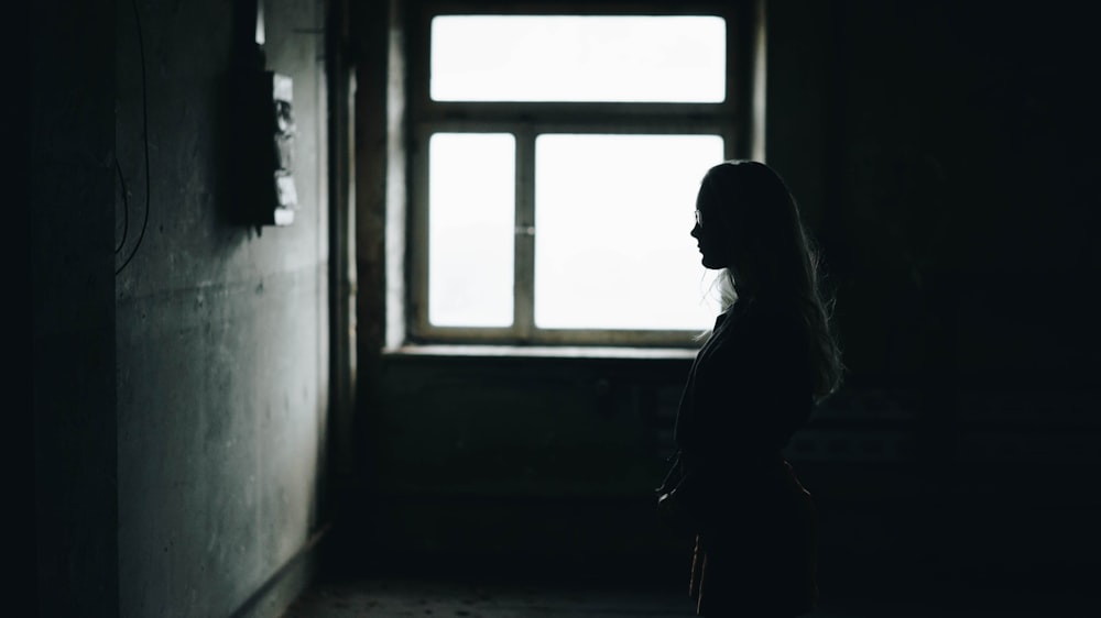 silhouette of woman standing while facing wall inside room