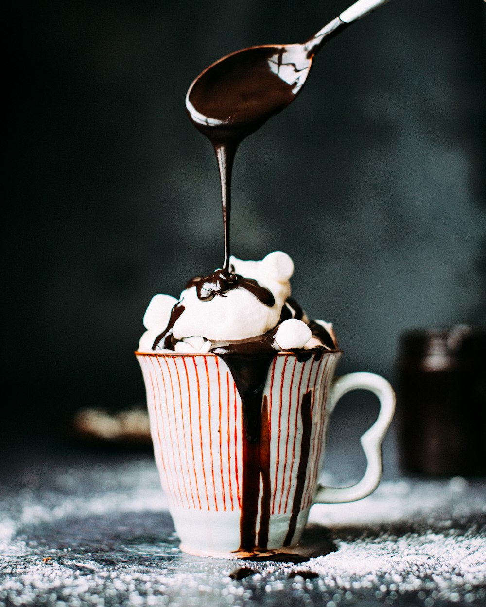 セラミックカップのバニラアイスクリームにチョコレートを注ぐ