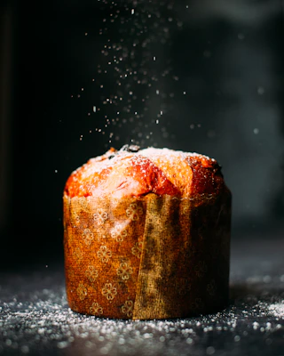 Freshly baked panettone cooling on a wooden rack with chocolate chips visible.