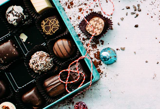 A delivery person handing over a beautifully wrapped box of chocolates to a smiling recipient at a cozy home entrance.