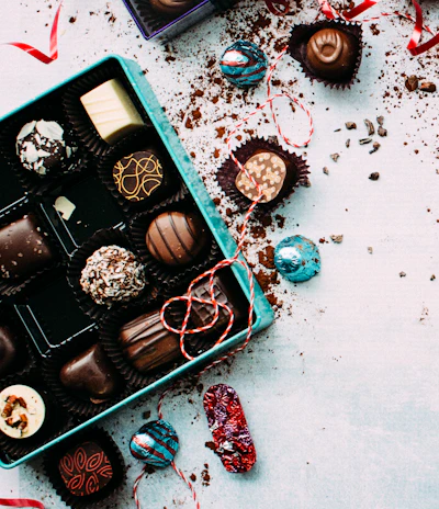 A delivery person handing over a beautifully wrapped box of chocolates to a smiling recipient at a cozy home entrance.