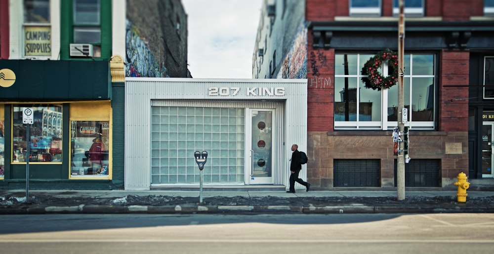 man walking beside 207 King building during daytime