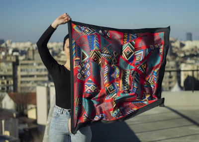 Artisan selecting premium fabrics with vibrant cityscape visible through the window.