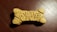 A dog biscuit shaped like a bone with the words 'Milk Bone' engraved on its surface, placed on a textured, dark brown background.