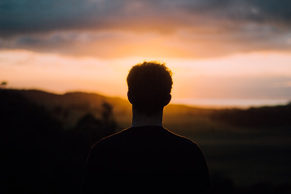 Silhouette eines Mannes, der dem Sonnenuntergang zugewandt ist