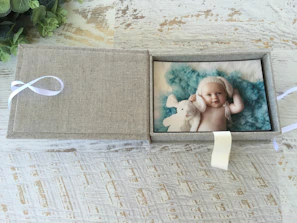 Close-up of a velvet-lined gift box revealing a personalized baby blanket and romper.