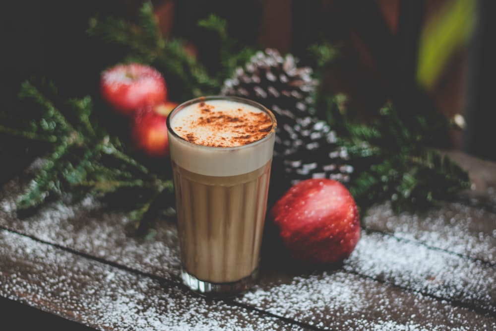 taza de campo de café con leche junto a manzana roja