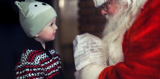 toddler in black sweater standing in front of Santa Claus