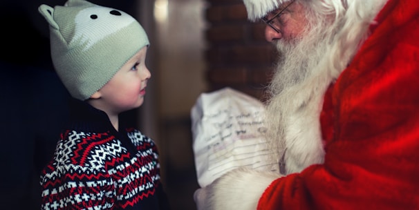 toddler in black sweater standing in front of Santa Claus