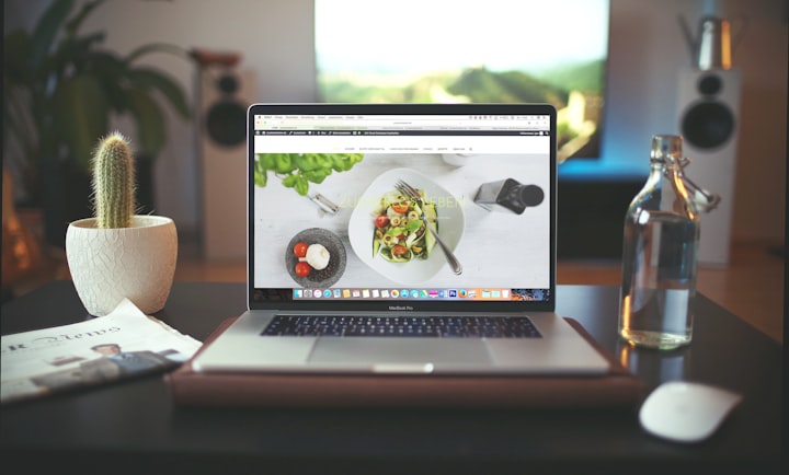 Image of a Mac showing a webpage on a nice desk with a succulent and water