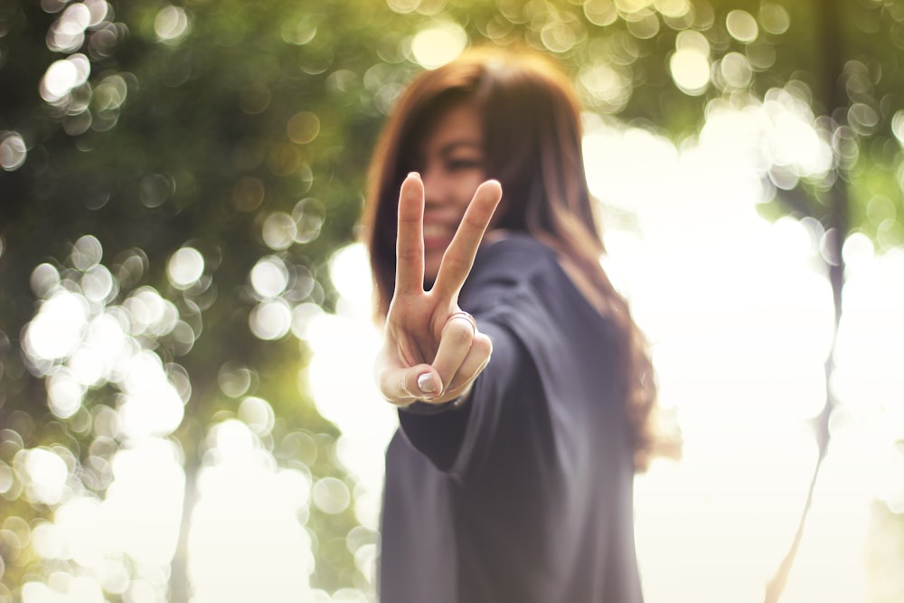 smiling woman making peace hand sign while standing
