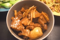 Close-up of a steaming bowl of kare kare with rich peanut sauce and tender oxtail