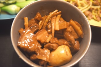Close-up of a steaming bowl of kare kare with rich peanut sauce and tender oxtail